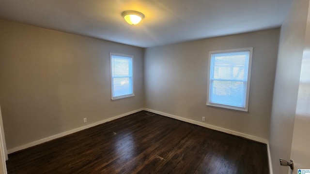 spare room featuring plenty of natural light and dark hardwood / wood-style floors