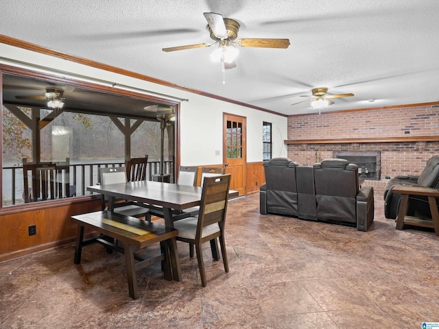 dining space with brick wall, a textured ceiling, ornamental molding, and wood walls