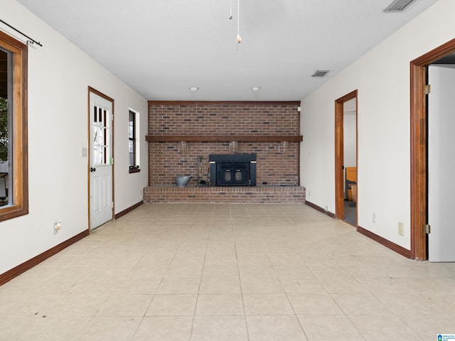 unfurnished living room with light tile patterned floors and a wood stove