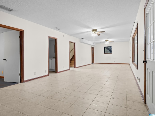 spare room featuring ceiling fan, light tile patterned flooring, and a textured ceiling