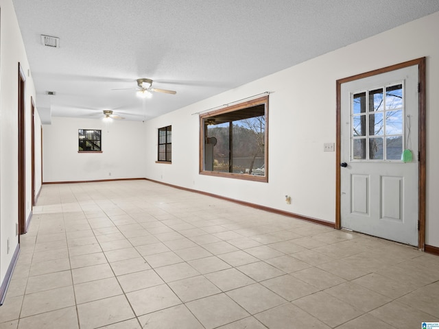 tiled empty room with ceiling fan and a textured ceiling