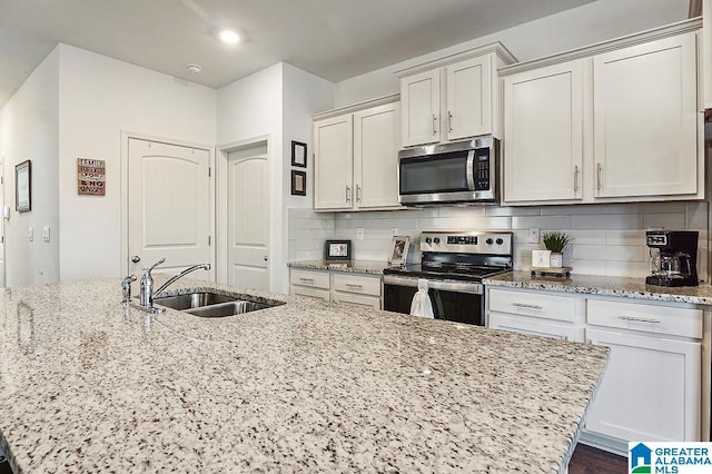 kitchen with light stone countertops, sink, white cabinets, and stainless steel appliances