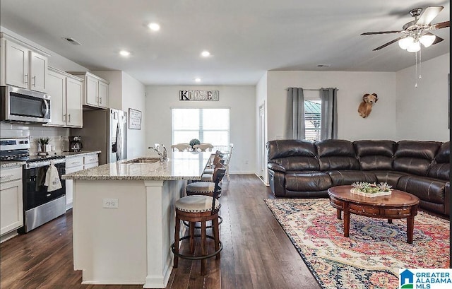 kitchen featuring a breakfast bar, sink, an island with sink, and appliances with stainless steel finishes