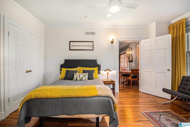 bedroom featuring hardwood / wood-style floors, ceiling fan, ornamental molding, and a closet