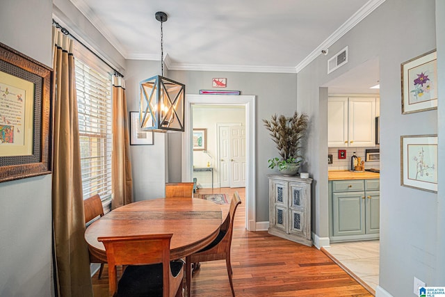 dining room featuring light wood-type flooring and ornamental molding