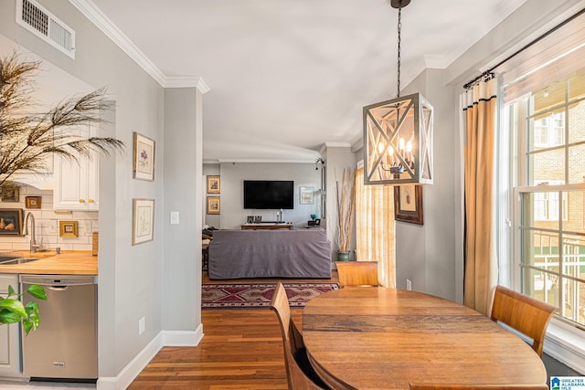 dining area featuring sink, an inviting chandelier, dark wood-type flooring, and ornamental molding