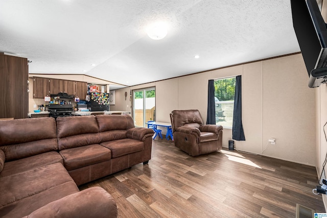 living room with a textured ceiling, crown molding, dark wood-type flooring, and vaulted ceiling