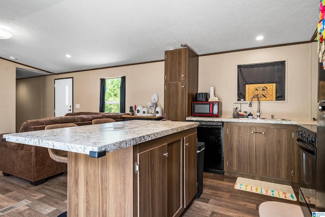 kitchen with a center island, black appliances, sink, ornamental molding, and dark hardwood / wood-style flooring