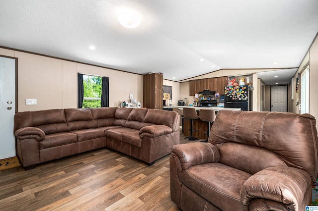 living room featuring hardwood / wood-style flooring, lofted ceiling, and crown molding