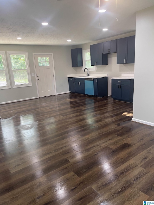 kitchen featuring dishwasher, blue cabinetry, dark wood-type flooring, and sink