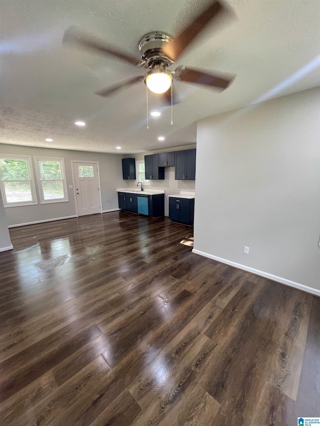 unfurnished living room featuring a textured ceiling, sink, and dark wood-type flooring