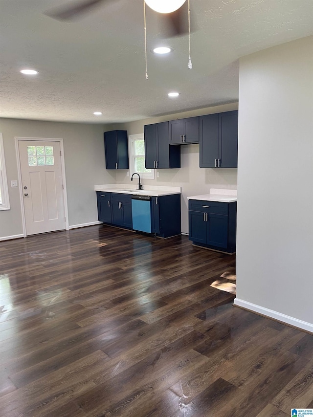 kitchen with blue cabinetry, dark hardwood / wood-style flooring, sink, and stainless steel dishwasher