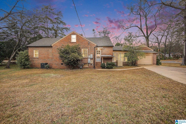 view of front of house with a yard, cooling unit, and a garage