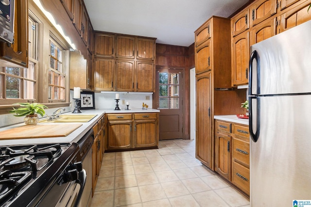 kitchen with dishwashing machine, light tile patterned floors, stainless steel refrigerator, and sink