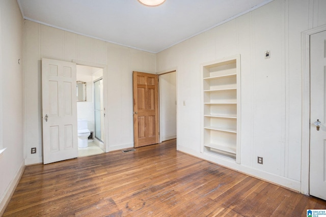 unfurnished bedroom featuring ensuite bath and dark hardwood / wood-style floors