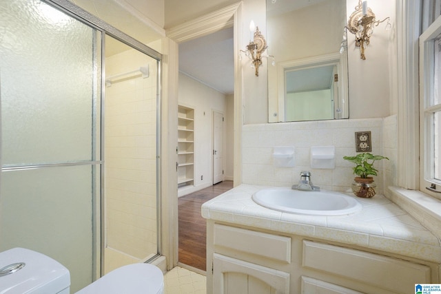 bathroom with backsplash, vanity, built in features, toilet, and a shower with shower door