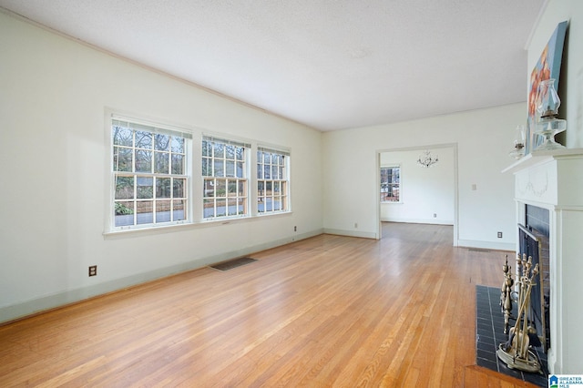 unfurnished living room featuring a wealth of natural light, light hardwood / wood-style flooring, and a notable chandelier