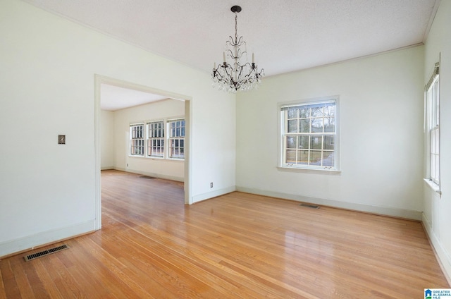 empty room with a chandelier and light hardwood / wood-style floors