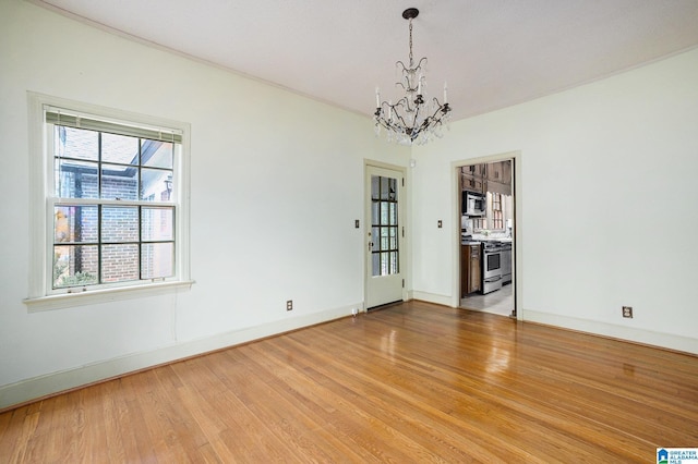 spare room with a chandelier and hardwood / wood-style flooring