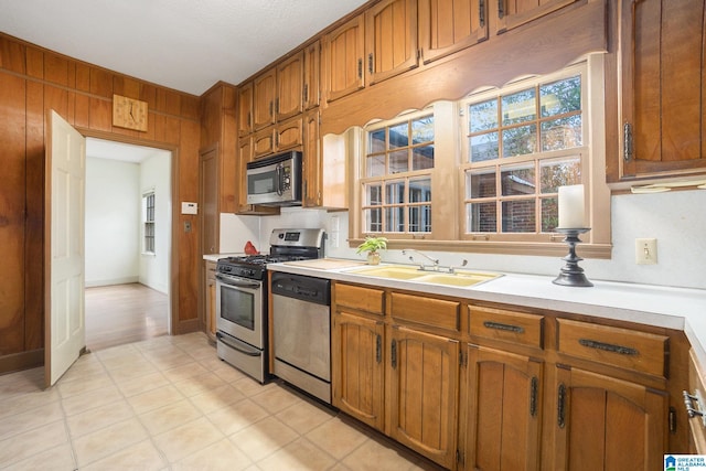 kitchen with wooden walls, sink, and appliances with stainless steel finishes