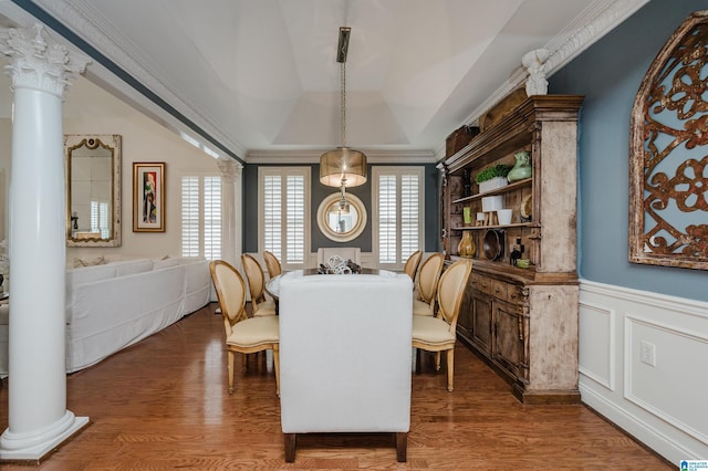 dining area with a tray ceiling, hardwood / wood-style flooring, decorative columns, and ornamental molding