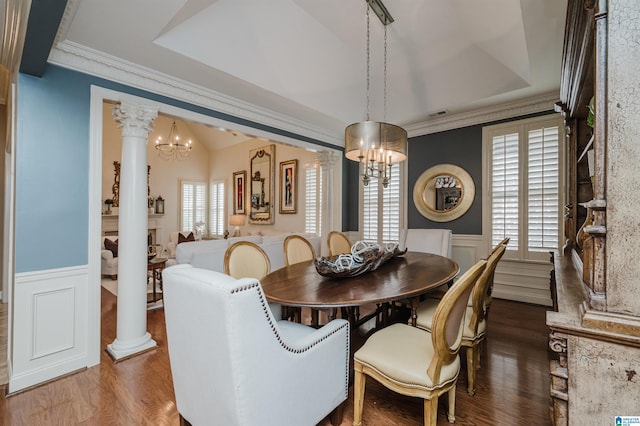 dining area with decorative columns, an inviting chandelier, ornamental molding, and hardwood / wood-style flooring