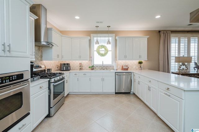 kitchen with decorative light fixtures, stainless steel appliances, white cabinetry, and wall chimney range hood