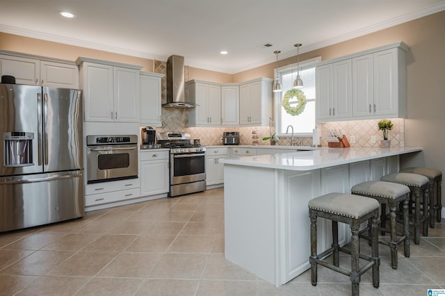 kitchen with kitchen peninsula, stainless steel appliances, wall chimney range hood, pendant lighting, and a breakfast bar area