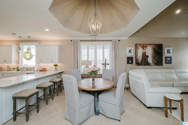 tiled dining space featuring a tray ceiling, an inviting chandelier, crown molding, and sink