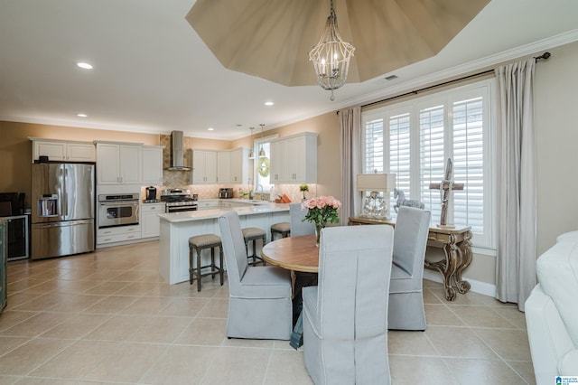 tiled dining room with ornamental molding, a tray ceiling, and a chandelier