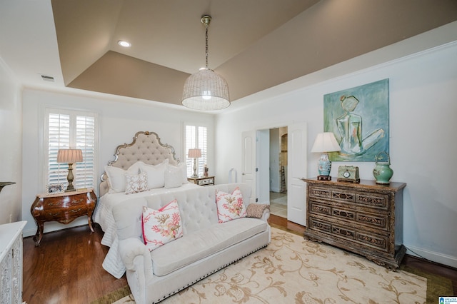 bedroom with hardwood / wood-style flooring, a raised ceiling, and multiple windows