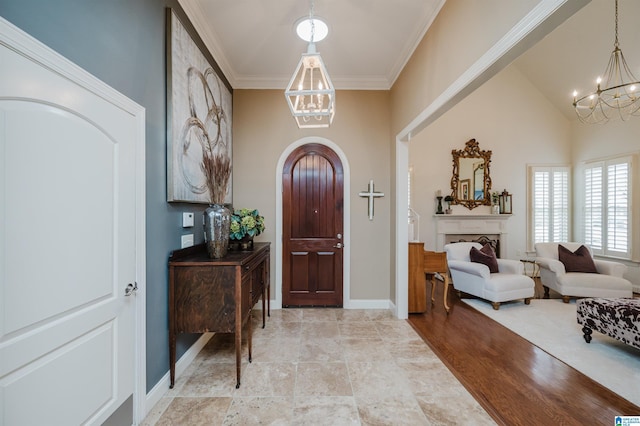 entryway with crown molding, high vaulted ceiling, and an inviting chandelier