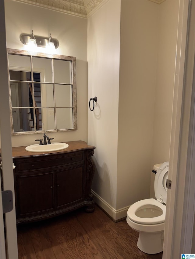 bathroom with vanity, hardwood / wood-style flooring, toilet, and ornamental molding