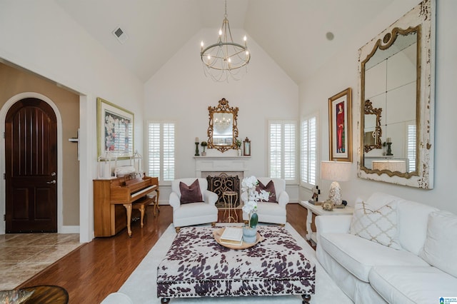 living room with a wealth of natural light, an inviting chandelier, lofted ceiling, and hardwood / wood-style flooring