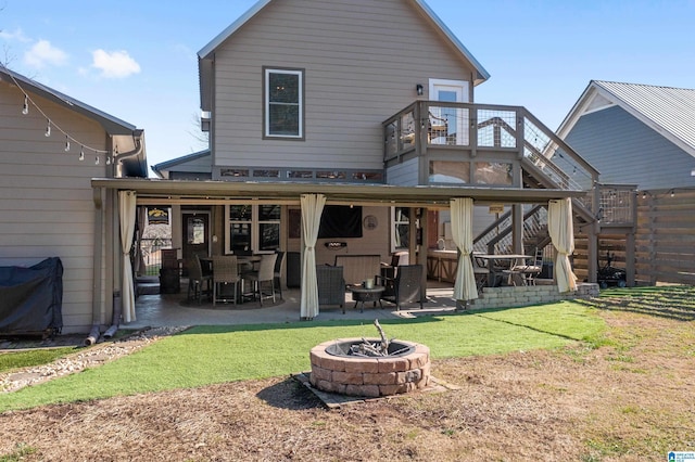 rear view of house with a lawn, a patio, and an outdoor fire pit