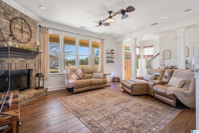 living room with ornate columns, ceiling fan, crown molding, dark wood-type flooring, and a fireplace