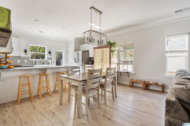 dining area with light hardwood / wood-style floors, a healthy amount of sunlight, and crown molding