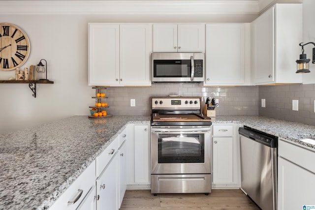 kitchen featuring white cabinets, decorative backsplash, stainless steel appliances, and light stone counters