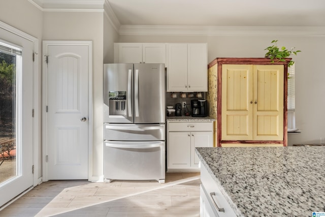 kitchen featuring white cabinets, stainless steel refrigerator with ice dispenser, light stone countertops, tasteful backsplash, and a healthy amount of sunlight