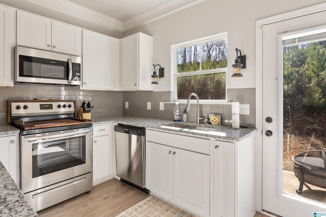 kitchen with light stone counters, white cabinetry, sink, and appliances with stainless steel finishes