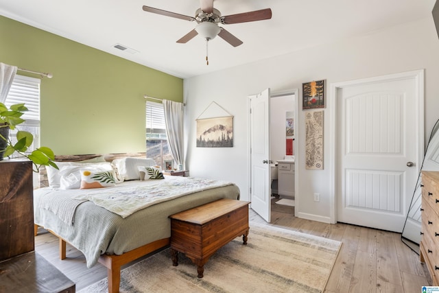 bedroom with ceiling fan, ensuite bathroom, and light hardwood / wood-style flooring