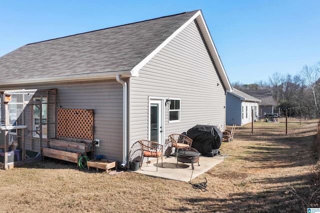 back of property with a lawn, a patio area, and an outdoor fire pit