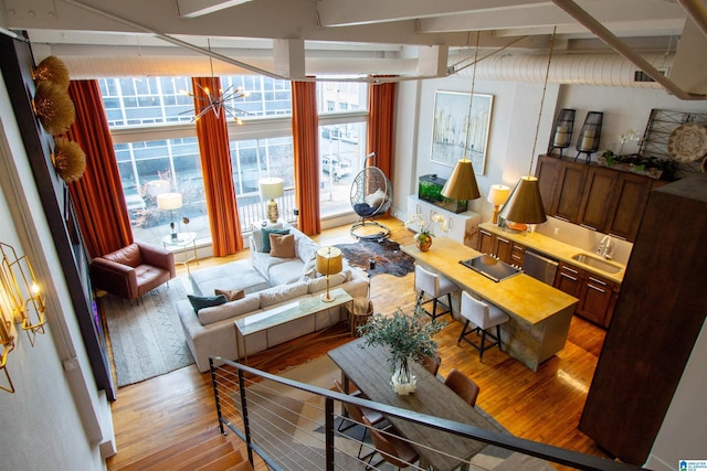 living room with floor to ceiling windows, light hardwood / wood-style flooring, a chandelier, and sink