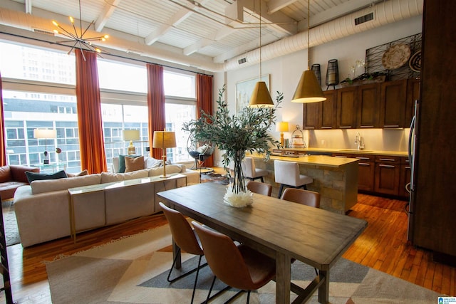 dining room with beamed ceiling, dark hardwood / wood-style flooring, sink, and an inviting chandelier