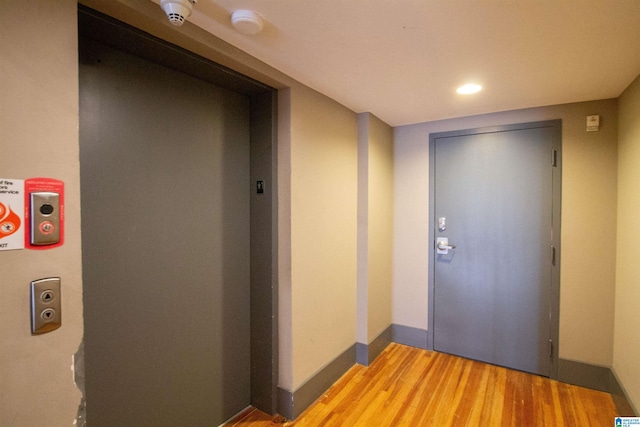 corridor with wood-type flooring and elevator