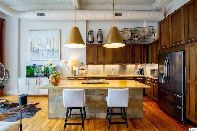 kitchen featuring decorative light fixtures, stainless steel appliances, hardwood / wood-style flooring, and a kitchen breakfast bar