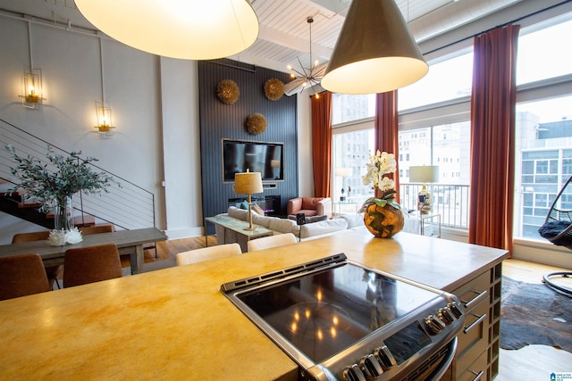 kitchen featuring hardwood / wood-style flooring, stainless steel range with electric cooktop, beamed ceiling, and a chandelier