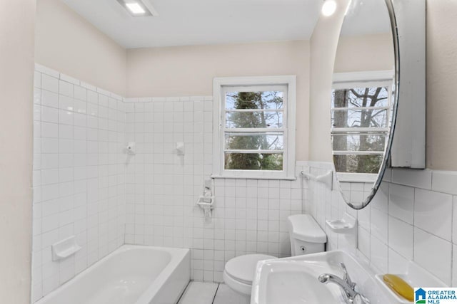 bathroom with sink, toilet, and tile walls