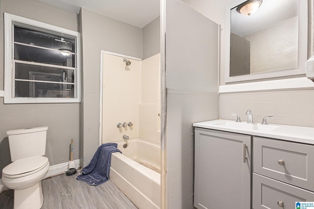 full bathroom featuring hardwood / wood-style flooring, toilet, vanity, and washtub / shower combination