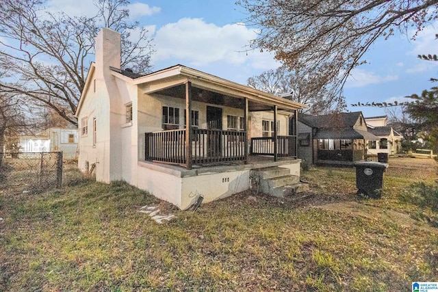 rear view of property with covered porch and a yard